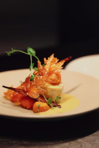 a white plate with a dish of food on a table at Villa de Duinen - Adults Only in Noordwijk aan Zee