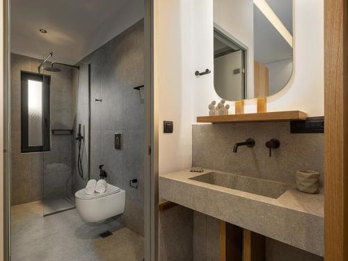 a bathroom with a sink and a toilet and a mirror at Nontas suites in Kato Daratso