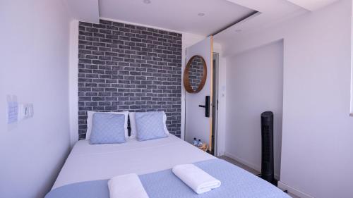 a bedroom with a bed with blue pillows and a brick wall at airport room in Lisbon