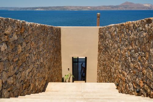 a stone wall with a door in front of the ocean at ARion Aesthesis Superior Villa Heated Pool in Kókkinon Khoríon