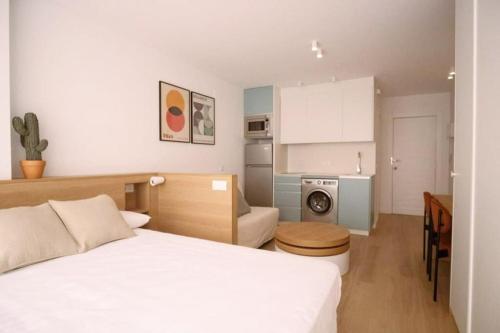 una camera da letto con un letto bianco e una cucina di Luminoso estudio con vistas al mar a Las Canteras