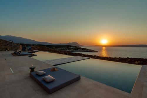 a pool with the sunset in the background at ARion Aesthesis Superior Villa Heated Pool in Kókkinon Khoríon