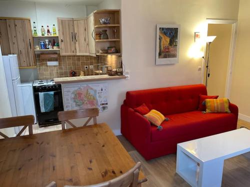 un salon avec un canapé rouge et une cuisine dans l'établissement Coquelicot du Canal Saint-Martin, à Paris