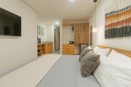 a bedroom with a large white bed with pillows at Cozy apartment with pool in Bacalar Center in Bacalar