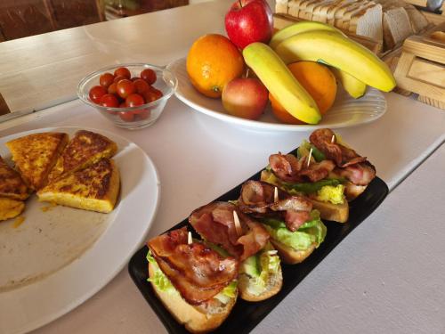 a table with a plate of toast and a plate of fruit at Hotel Bodegón de Peñíscola in Peñíscola