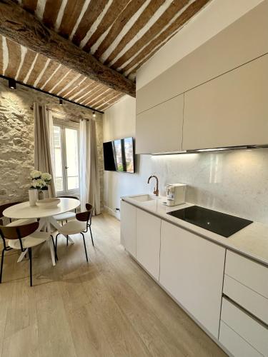 une cuisine avec des armoires blanches et une table avec des chaises dans l'établissement New Charming Apartment Old Town, à Antibes