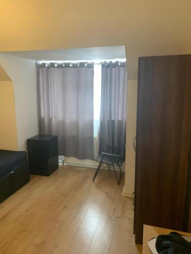 Una sala de estar con una silla y una ventana. en At Apex House, en Dagenham