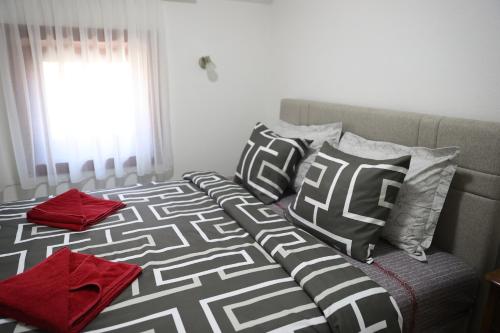 a bed with black and white pillows and a window at Ego apartmanii in Ćuprija