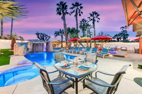 a patio with a table and chairs next to a pool at Happy Hour in Bermuda Dunes