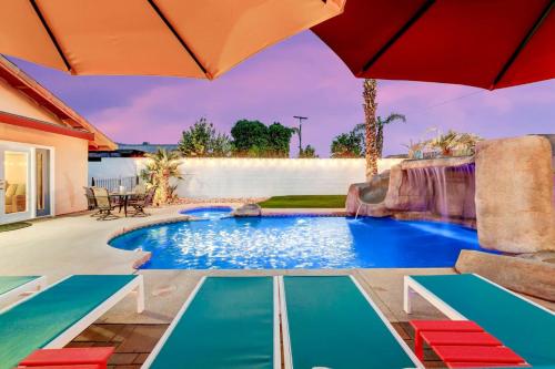 a swimming pool in a backyard with an umbrella at Happy Hour in Bermuda Dunes