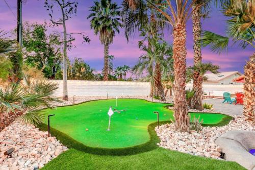 a golf course with palm trees and a putting green at Happy Hour in Bermuda Dunes