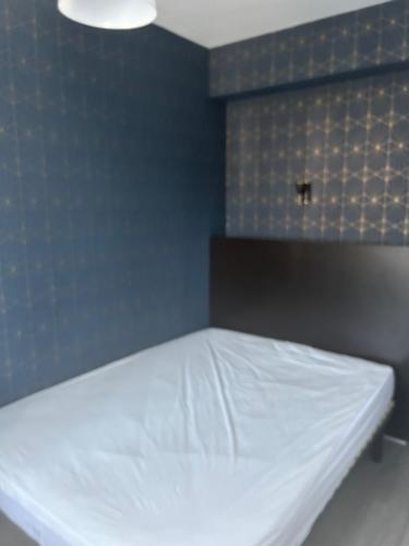 - un lit blanc dans une chambre dotée d'un mur bleu dans l'établissement Locations Saint Palais, à Saint-Palais-sur-Mer