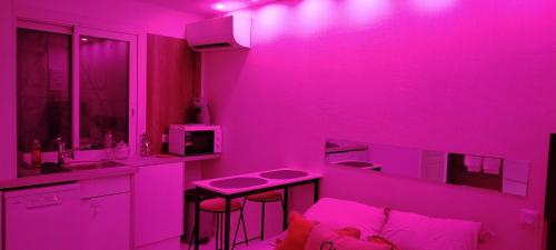 una stanza rosa con un lavandino e un tavolo di studio cosy balneo avec jardin a Le Barcarès