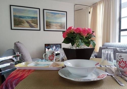 a table with a vase with pink roses on it at Suite con lunas y Sol del Río Amazonas, por Reforma 222 in Mexico City