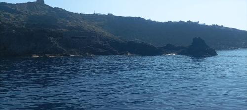 a large body of water with a mountain in the background at dammuso rosa in Pantelleria