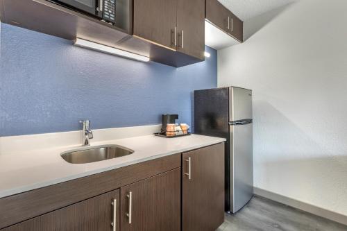 a kitchen with a sink and a refrigerator at Greenville Pelham Inn by IHG in Greenville