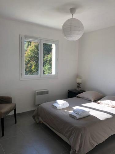 une chambre blanche avec un lit et une fenêtre dans l'établissement Dépendance en Provence, à Simiane-Collongue