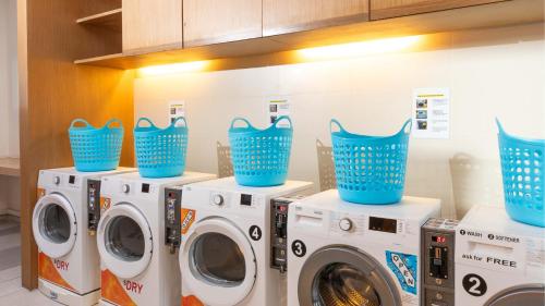 a laundry room with four washing machines and blue baskets at Holiday Inn Express Phuket Patong Beach Central by IHG in Patong Beach