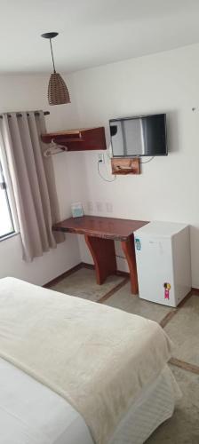 a bedroom with a desk and a bed in a room at Pousada Morada do Sol in Camocim