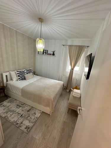 a white bedroom with a bed and a chandelier at Boutique Apartment in Bucharest