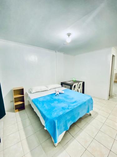 a bedroom with a bed with a blue blanket at La Pearla Place Boracay Dmall in Boracay