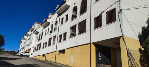 a white and yellow building with a van parked outside at El ático de María in Ruidera