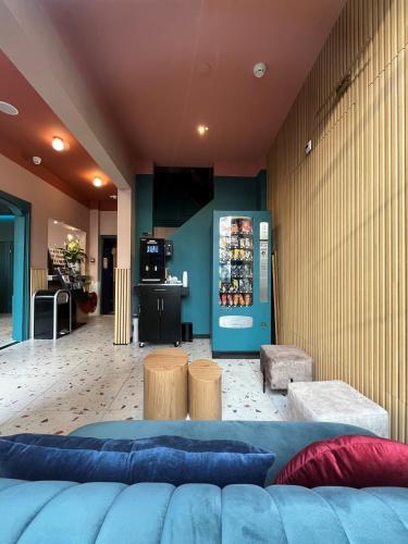 a lobby with a blue couch and tables and a tv at Heart of Amsterdam Hostel in Amsterdam