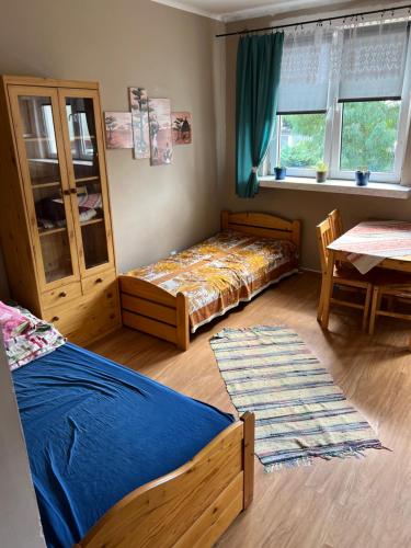a bedroom with two beds and a table and window at Pokoje przy Tamie in Włocławek