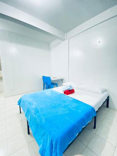 a white room with a bed with a blue blanket on it at La Pearla Place Boracay Dmall in Boracay