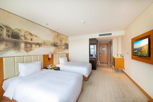 a hotel room with two beds and a television at Junluxe Hotel Guangzhou Science City-Free Shuttle Bus Service to Guangzhou Canton Fair in Guangzhou