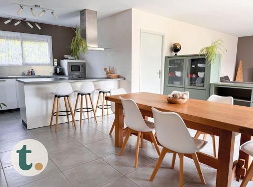 a kitchen with a wooden table and white chairs at Tranquiloue - Maison moderne - Proche PuyduFou in Mesnard-la-Barotière