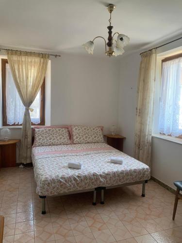 a bedroom with a bed in a room with windows at Lûc dal Aur in Sùtrio