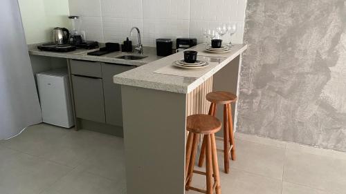 a kitchen with a counter with two stools and a sink at Villa Mavi - Praia do Rosa in Imbituba