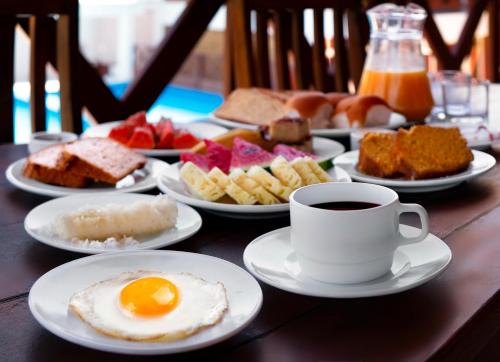 a table with plates of breakfast foods and a cup of coffee at Vila Jeri Hotel in Jericoacoara