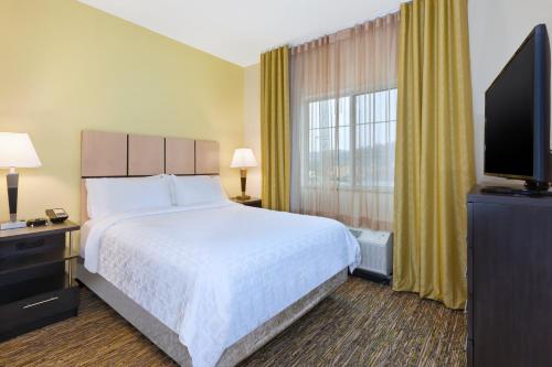 a hotel room with a bed and a flat screen tv at Candlewood Suites Morgantown-Univ West Virginia by IHG in Morgantown