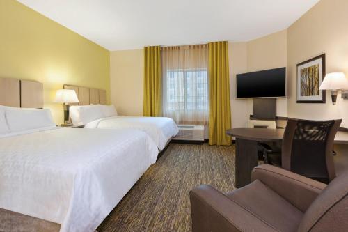 a hotel room with two beds and a desk and a tv at Candlewood Suites Morgantown-Univ West Virginia by IHG in Morgantown