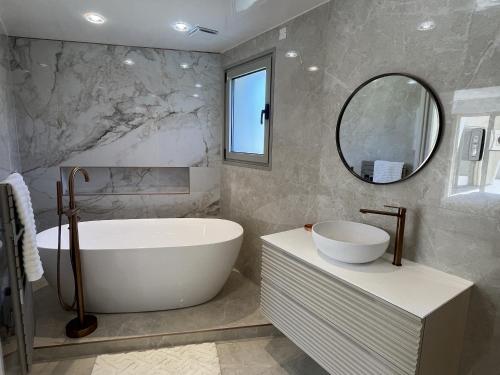 une salle de bain avec une baignoire, un lavabo et un miroir dans l'établissement Villa neuve avec piscine 240m2 capacite 10 pers,, à Fréjus