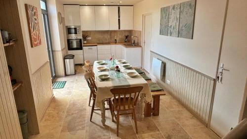 une table de salle à manger avec des chaises et une cuisine dans l'établissement Chambre dans une maison partagée rustic-chic avec jardin 'CoAbbita', à Abbeville