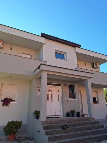 una casa con una puerta blanca y escaleras en Rooms Džeba, en Međugorje