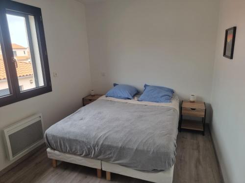 une chambre avec un lit avec des oreillers bleus et une fenêtre dans l'établissement Maison pour 6p - 3ch - piscine privée - au calme, à Argelès-sur-Mer