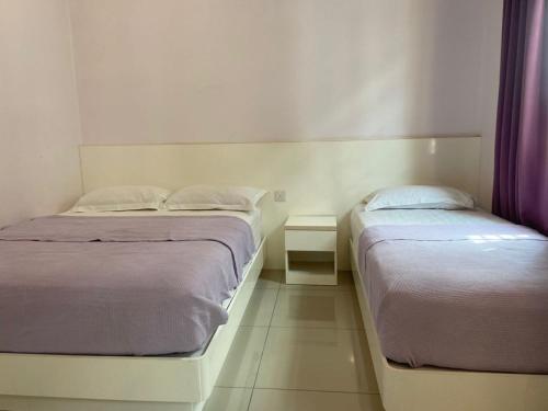 two beds in a small room with purple curtains at Lavender Riverside Hotel in Melaka
