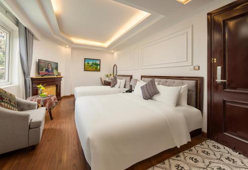 a bedroom with two white beds and a couch at Sapa Praha Hotel in Sa Pa
