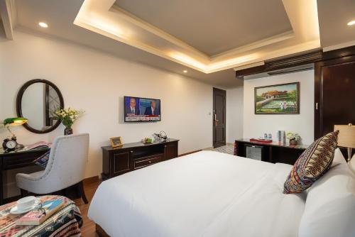 a bedroom with a white bed and a desk and a mirror at Sapa Praha Hotel in Sa Pa