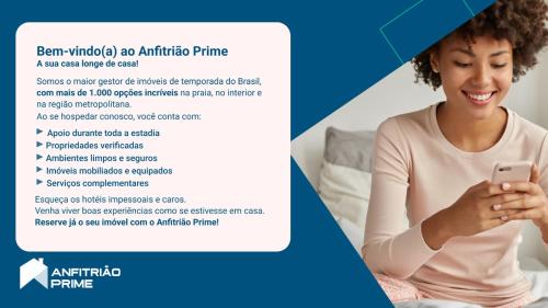 a woman sitting on a bed looking at a cell phone at Casa c otima localizacao em Teixeira de Freitas-BA in Teixeira de Freitas