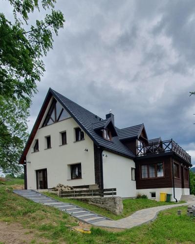 a large white house with a black roof at Nasza Jodłówka in Jodłów