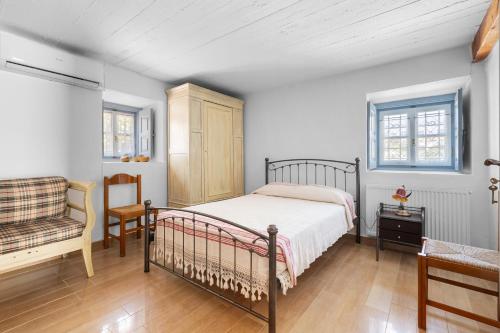 a bedroom with a bed and a chair at Votsalo Spetses in Spetses