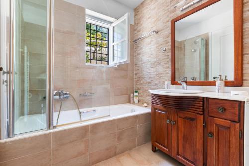 a bathroom with a tub and a sink and a mirror at Votsalo Spetses in Spetses