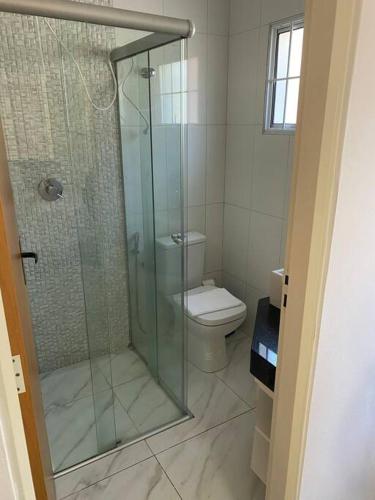 a bathroom with a toilet and a glass shower at Casa Ribeiro Aconchegante no centro de Araxá in Araxá