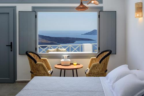 a bedroom with a bed and a table and chairs at Elia Caldera Suites in Fira