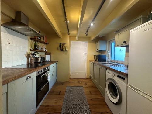 Una cocina con lavadora y secadora. en Seaforth - Fisherman's Cottage, en Gorran Haven